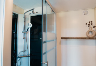 Moderne douche en stijlvolle plank met vaas in Big Lodge bij Holiday park De Boshoek, Nederland.