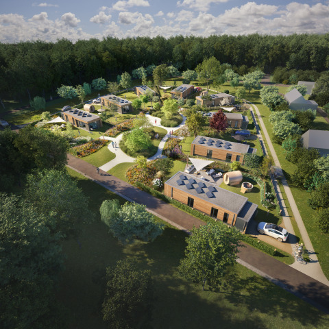 Vue aérienne d’un lodge moderne avec cabanes en bois, chemins paysagés, jardins et forêt environnante.