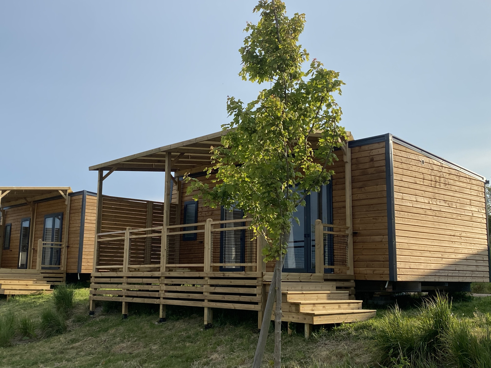Houten huisjes met veranda en trappen bij Cottage in Domaine Seasonova Saâne et Mer, Frankrijk in de zomer.