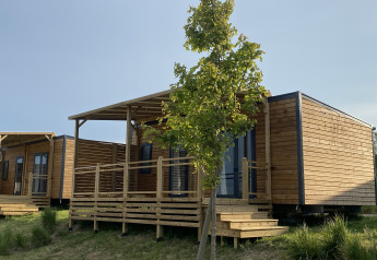 Træhytter med verandaer og trappe ved Domaine Seasonova Saâne et Mer Lodge, Frankrig, om sommeren.