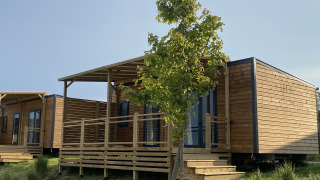 Træhytter med verandaer og trappe ved Domaine Seasonova Saâne et Mer Lodge, Frankrig, om sommeren.