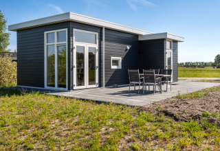 Chalet Turfsteker moderno en De Tien Heugten, Países Bajos, exterior oscuro y mesa de jardín en la terraza.