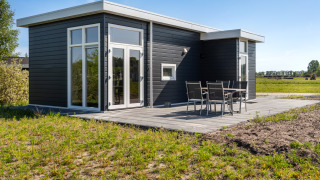 Chalet Turfsteker moderno en De Tien Heugten, Países Bajos, exterior oscuro y mesa de jardín en la terraza.
