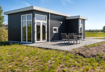 Modern Turfsteker Chalet bij De Tien Heugten, Nederland, met donkere gevel, terras en grote ramen.