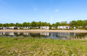 View of Turfsteker Chalet at De Tien Heugten in the Netherlands, with a lakeside, greenery, and holiday homes.