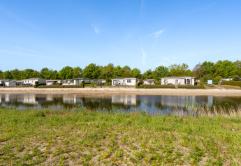 View of Turfsteker Chalet at De Tien Heugten in the Netherlands, with a lakeside, greenery, and holiday homes.