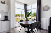 Modern dining area inside Turfsteker Chalet at De Tien Heugten in the Netherlands, overlooking a natural view.
