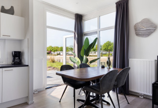 Comedor moderno en el Turfsteker Chalet de De Tien Heugten, Países Bajos, con grandes ventanales al exterior.