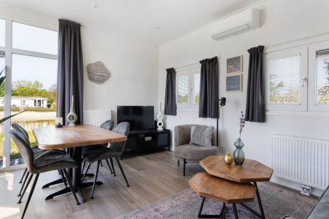 Modernes Wohnzimmer im Turfsteker Chalet bei De Tien Heugten, Niederlande, mit Esstisch und gemütlicher Einrichtung.