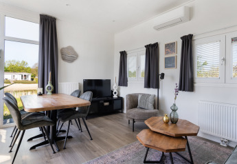 Moderne woonkamer in Turfsteker Chalet bij De Tien Heugten, Nederland, met eettafel en sfeervol interieur.