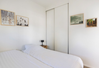 Slaapkamer in Turfsteker Chalet bij De Tien Heugten, Nederland, met dubbel bed en muurkunst decor.