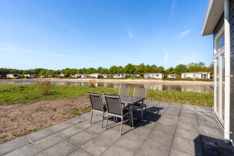 Terrasse des Turfsteker Chalets im De Tien Heugten, Niederlande, mit Blick auf einen Teich und Chalets.