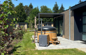 Private Whirlpool-Terrasse neben einer modernen Hütte im Batenburgh Deluxe, Veluwepark de Bosgraaf, Niederlande.