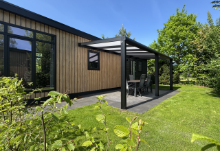 Moderne Sunlodge met overdekt terras bij vakantiepark 't Rheezerwold in Nederland, omringd door groen.
