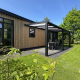 Sunlodge moderna con patio coperto al Holiday Park 't Rheezerwold nei Paesi Bassi, circondata dal verde.