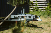Primo piano di un rimorchio con scritta KLAPKOT.NL accanto a una tiny house a De Klepperstee, Paesi Bassi.