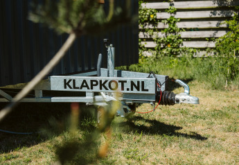 Gros plan sur une remorque portant KLAPKOT.NL, à côté d'une tiny house au parc De Klepperstee, Pays-Bas.