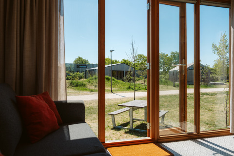 Uitzicht vanuit Klapkot C20 tiny house met open glazen deur, picknicktafel en groen bij De Klepperstee.
