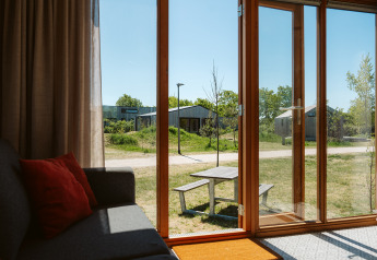 Uitzicht vanuit Klapkot C20 tiny house met open glazen deur, picknicktafel en groen bij De Klepperstee.