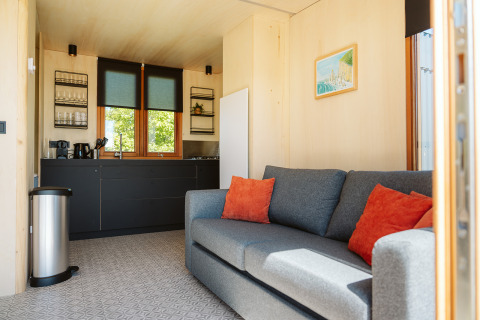 Modernes Wohnzimmer und Küchenzeile im Klapkot C20 Tiny House im Ferienpark De Klepperstee, Niederlande.