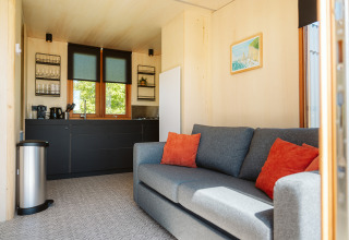 Soggiorno moderno e angolo cottura nel tiny house Klapkot C20 al Holiday park De Klepperstee, Olanda.