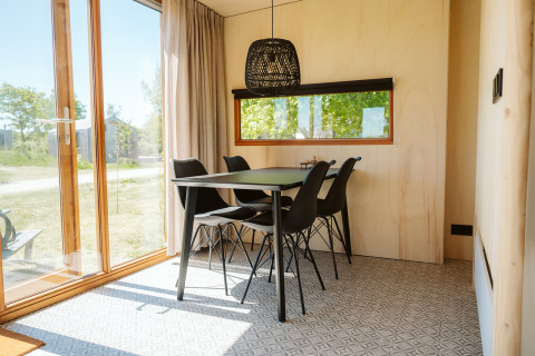 Comedor con mesa negra y cuatro sillas en la tiny house Klapkot C20 en el parque De Klepperstee, Países Bajos.