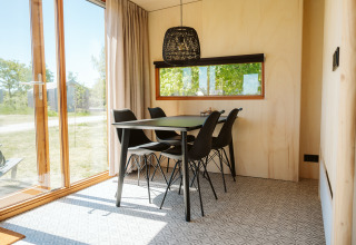 Comedor con mesa negra y cuatro sillas en la tiny house Klapkot C20 en el parque De Klepperstee, Países Bajos.
