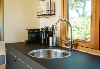 Évier de kitchenette moderne près d'une fenêtre dans la tiny house Klapkot C20, parc De Klepperstee, Pays-Bas.
