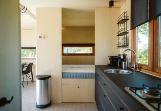Moderne en compacte keuken en slaapruimte in Klapkot C20 tiny house op Holiday park De Klepperstee, Nederland.