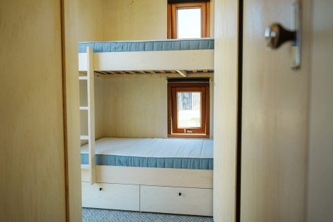 Blik op een kleine kamer met stapelbed en twee ramen in tiny house Klapkot C20 op De Klepperstee.