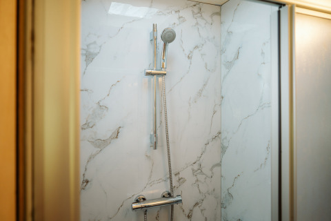 Moderne douche met marmerlook wanden en verstelbare douchekop in Klapkot C20, De Klepperstee, Nederland.