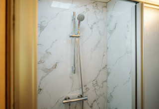 Moderne douche met marmerlook wanden en verstelbare douchekop in Klapkot C20, De Klepperstee, Nederland.