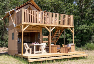 Two-story wooden cabin with balcony and patio at Domaine Bonneblond, Auvergne-Rhône-Alpes, France.