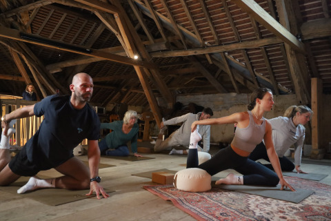Een groep doet yoga in een rustieke zolder bij Domaine Bonneblond vakantiepark in Auvergne-Rhône-Alpes, Frankrijk.