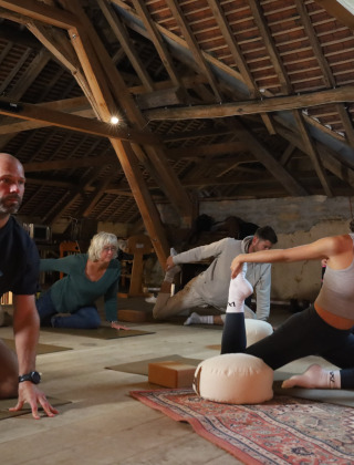 Un grupo de personas practica yoga en un ático rústico en Domaine Bonneblond, Auvergne-Rhône-Alpes, Francia.