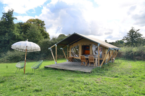 Glamping tent met houten terras, stoelen en parasol op Domaine Bonneblond in Auvergne-Rhône-Alpes, Frankrijk.