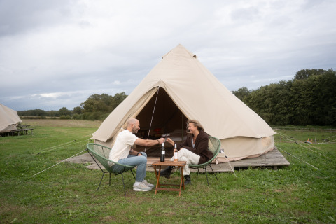 Koppel drinkt wijn voor een grote tent in Domaine Bonneblond, vakantiepark in Auvergne-Rhône-Alpes, Frankrijk.