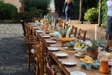 Lang træspisebord udendørs i Domaine Bonneblond, dækket op til brunch med kager, frugt og saft.