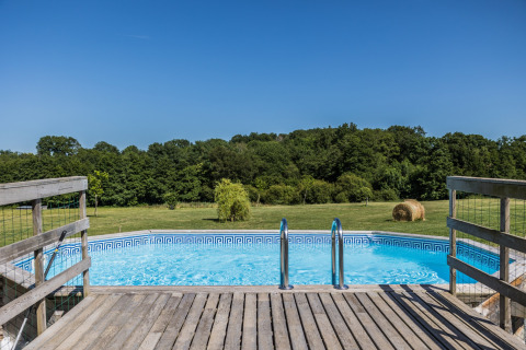 Uitzicht op een zwembad met houten terras en velden bij Domaine Bonneblond in Auvergne-Rhône-Alpes, Frankrijk.