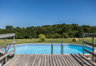 Vue sur une piscine avec terrasse en bois et champs ouverts au Domaine Bonneblond en Auvergne-Rhône-Alpes.