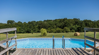 Vista de una piscina con terraza de madera y campo abierto en Domaine Bonneblond, Auvergne-Rhône-Alpes, Francia.