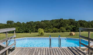 Vista de una piscina con terraza de madera y campo abierto en Domaine Bonneblond, Auvergne-Rhône-Alpes, Francia.