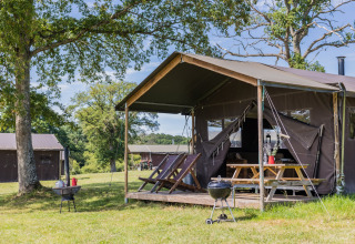 Luxury tent camping at Domaine Bonneblond with wooden deck and grill in scenic Auvergne-Rhône-Alpes, France.