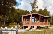 Moderna cabaña Lakehouse Scandi en Wilsumer Berge, Alemania, con terraza y tumbonas en entorno natural.