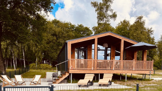 Modern Lakehouse Scandi bij Wilsumer Berge, Duitsland, met houten terras en ligstoelen in groene omgeving.