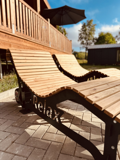 Chaises longues en bois avec 'Relax' devant Lakehouse Scandi à Wilsumer Berge, Allemagne, par beau temps.