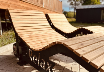Houten ligzetels met het woord 'Relax' bij Lakehouse Scandi aan Wilsumer Berge in Duitsland, zonnige dag.