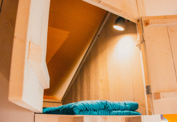 Acogedor rincón para dormir con paredes de madera y ropa de cama azul en Safari cottage en De Boshoek.