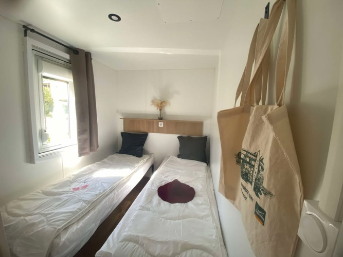 Habitación luminosa con dos camas individuales y bolsas de tela en Cottage de Domaine Seasonova Saâne et Mer, Francia.