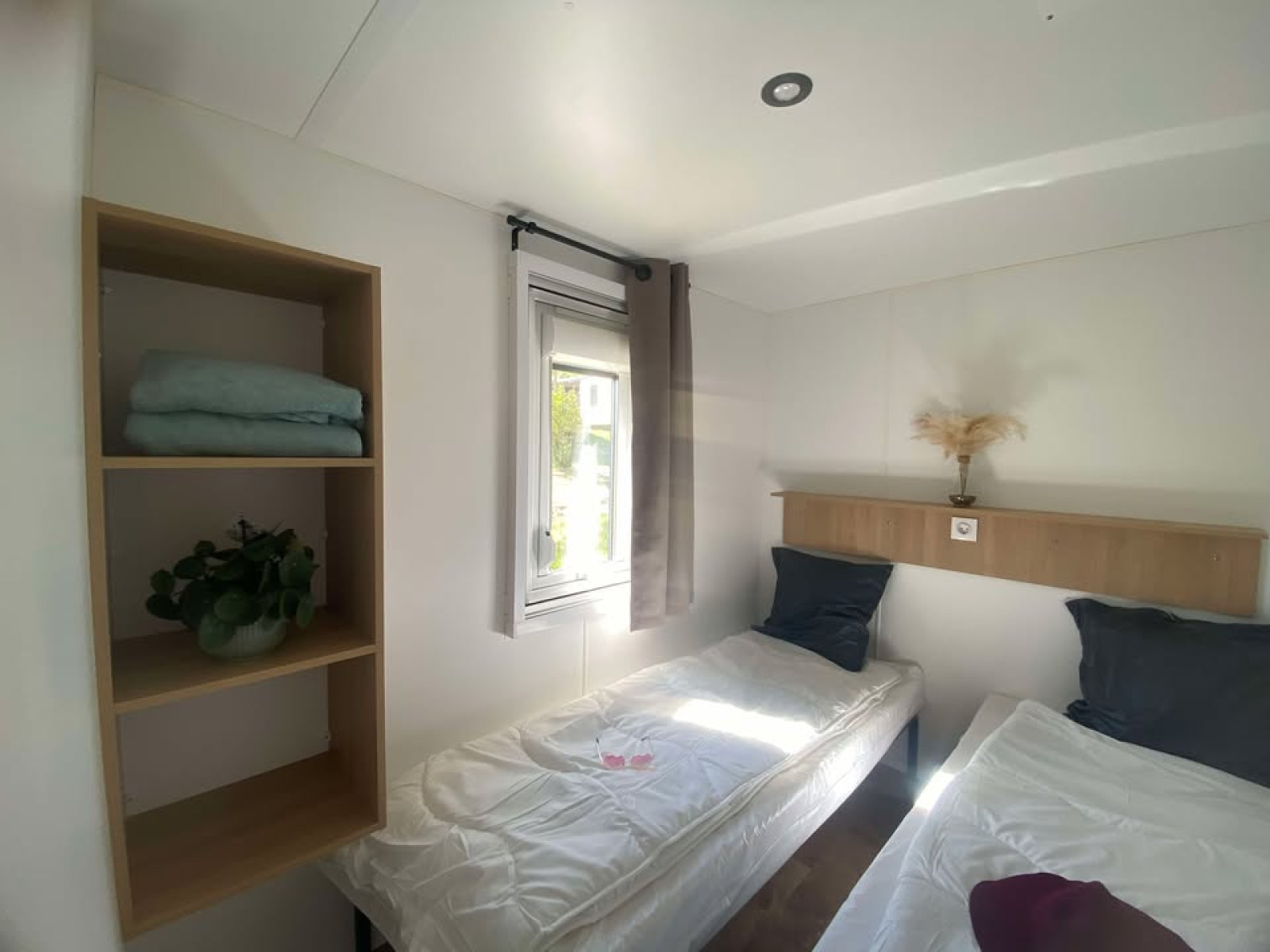 Lichte kamer met twee eenpersoonsbedden, venster, open planken en eenvoudige decoratie in het Cottage.